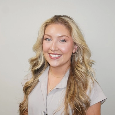 Haley Burns smiling in front of a white wall.